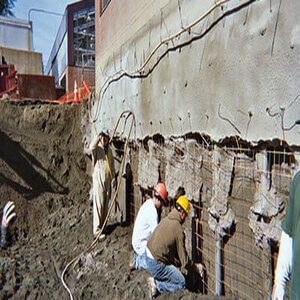 Team of foundation contractors working on a commercial buildings foundation refinishing the exterior